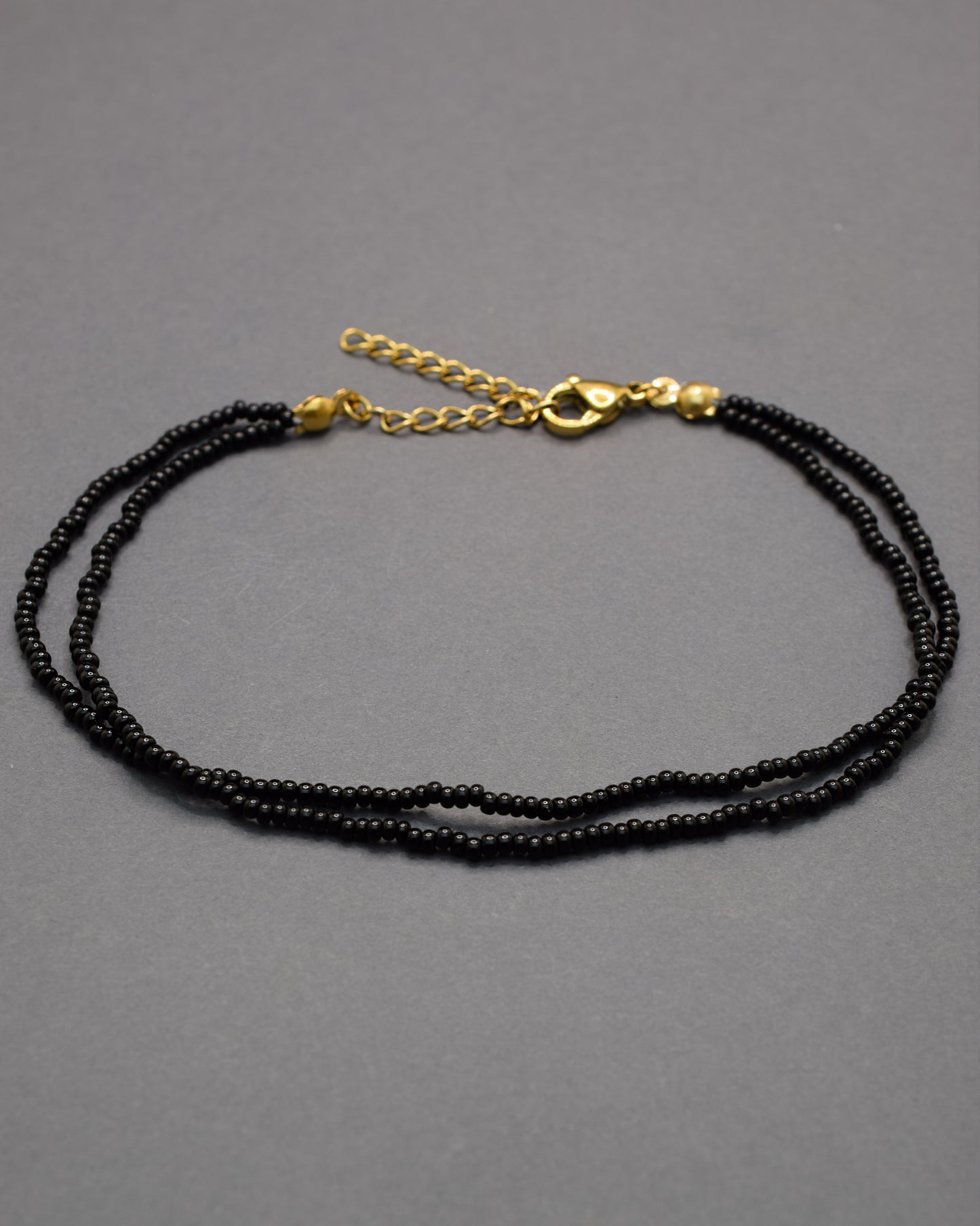Pulseira dupla de tornozelo com missangas pretas, elegante e intemporal, perfeita para um toque discreto e sofisticado no teu estilo.