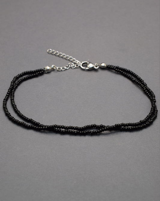 Pulseira dupla de tornozelo com missangas pretas, elegante e intemporal, perfeita para um toque discreto e sofisticado no teu estilo.