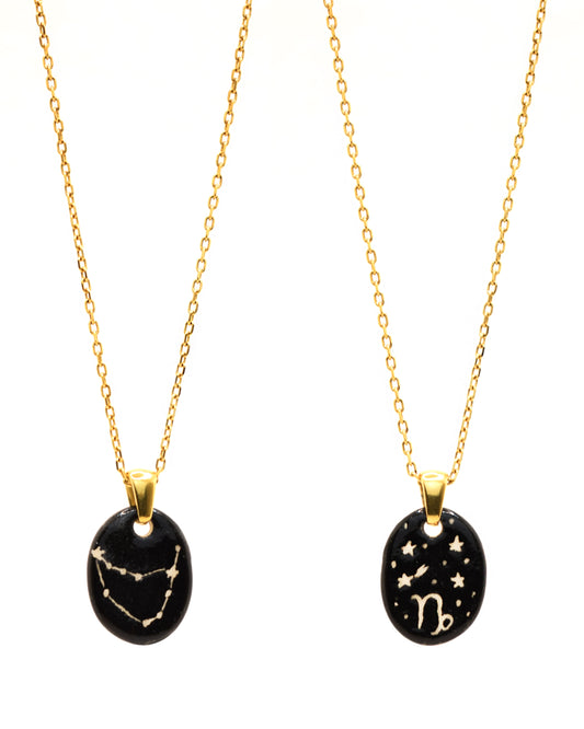 Colar sofisticado em aço dourado com pendente dupla-face esculpido em cerâmica, representando a constelação Capricórnio.