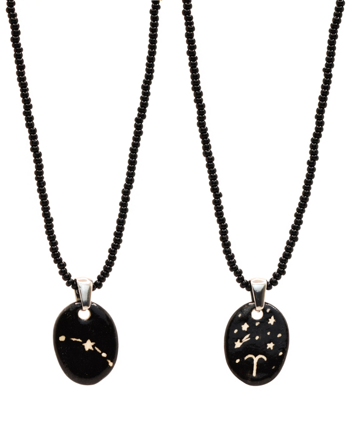 Colar elegante com pendente de cerâmica dupla-face representando a constelação Carneiro, adornado com missangas de vidro pretas para um toque sofisticado e misterioso.