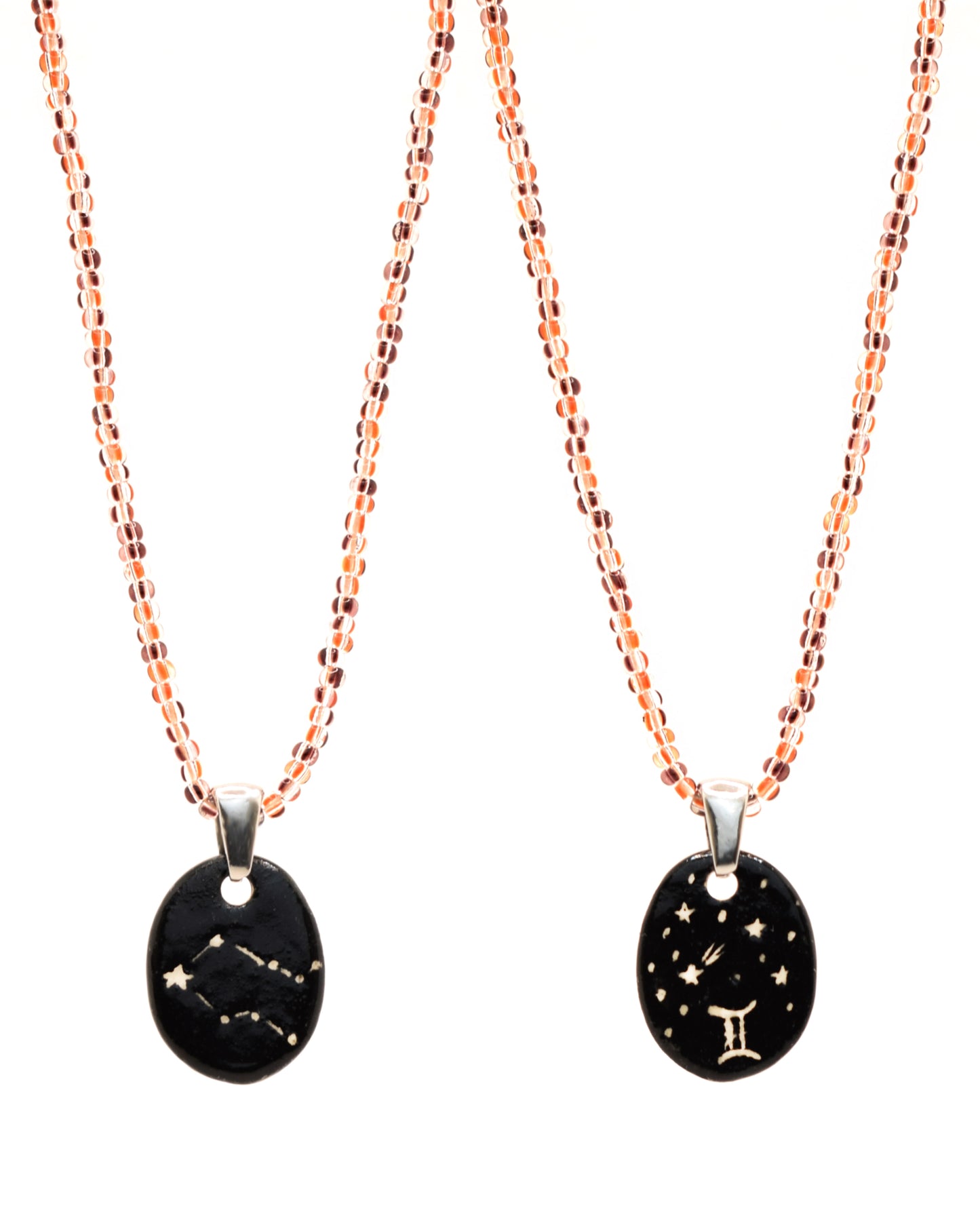 Colar elegante com pendente dupla-face esculpido em cerâmica, retratando a constelação de Gémeos, complementado por missangas listradas em tons castanhos para um toque de estilo e charme distintos.