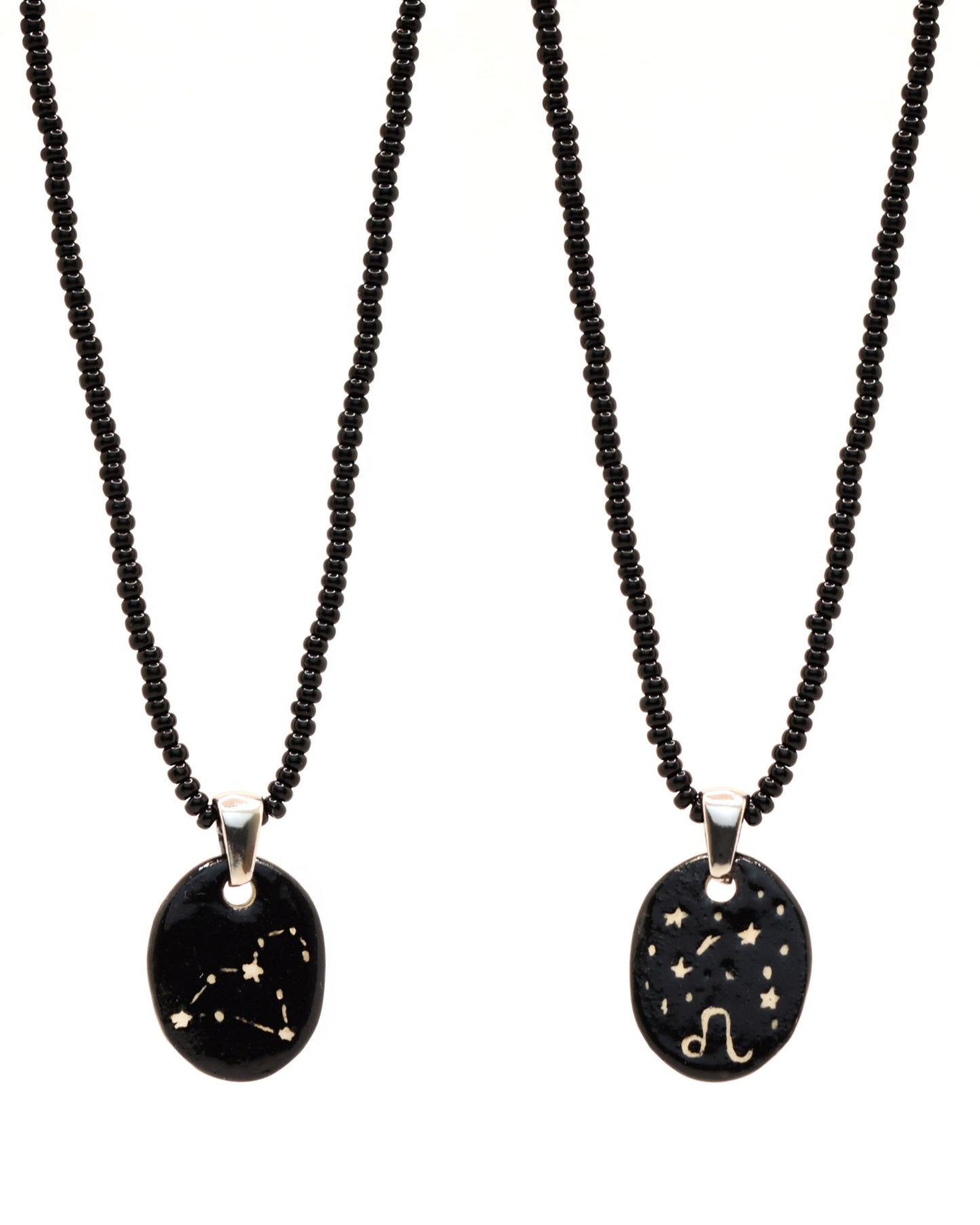 Colar elegante com pendente de cerâmica dupla-face representando a constelação Leão, adornado com missangas de vidro pretas para um toque sofisticado e misterioso.