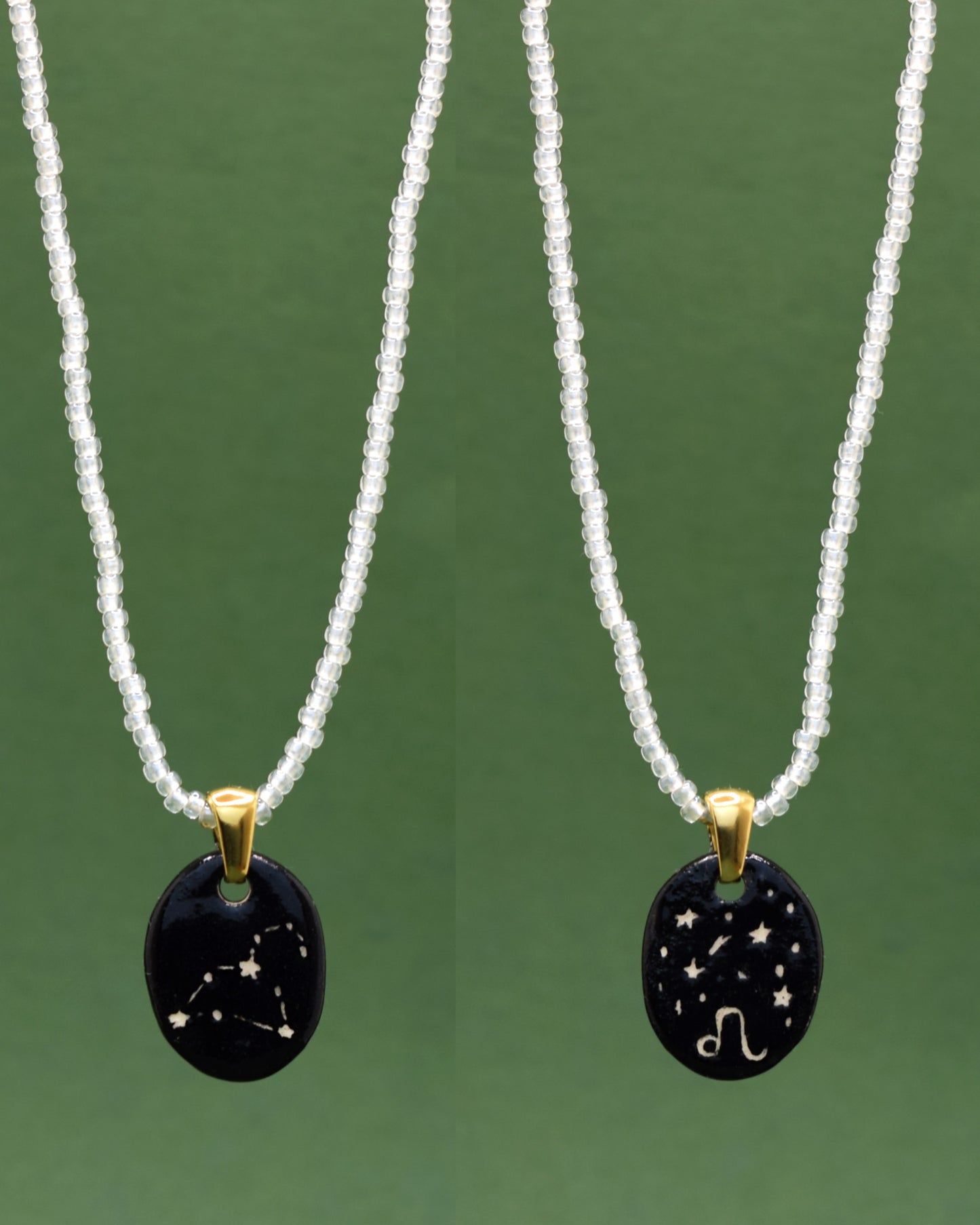 Colar refinado apresentando um pendente dupla-face esculpido em cerâmica, destacando a constelação de Leão, harmonizado com uma delicada corrente de missangas semitransparentes em branco para um toque de elegância etérea.