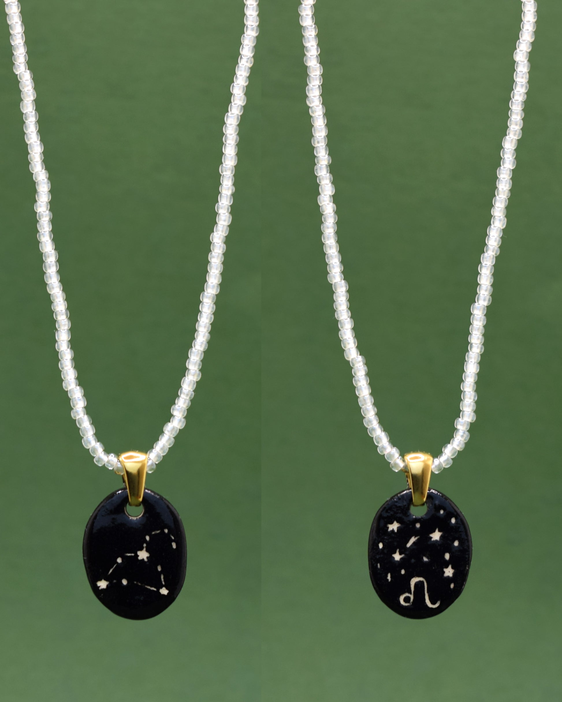 Colar refinado apresentando um pendente dupla-face esculpido em cerâmica, destacando a constelação de Leão, harmonizado com uma delicada corrente de missangas semitransparentes em branco para um toque de elegância etérea.