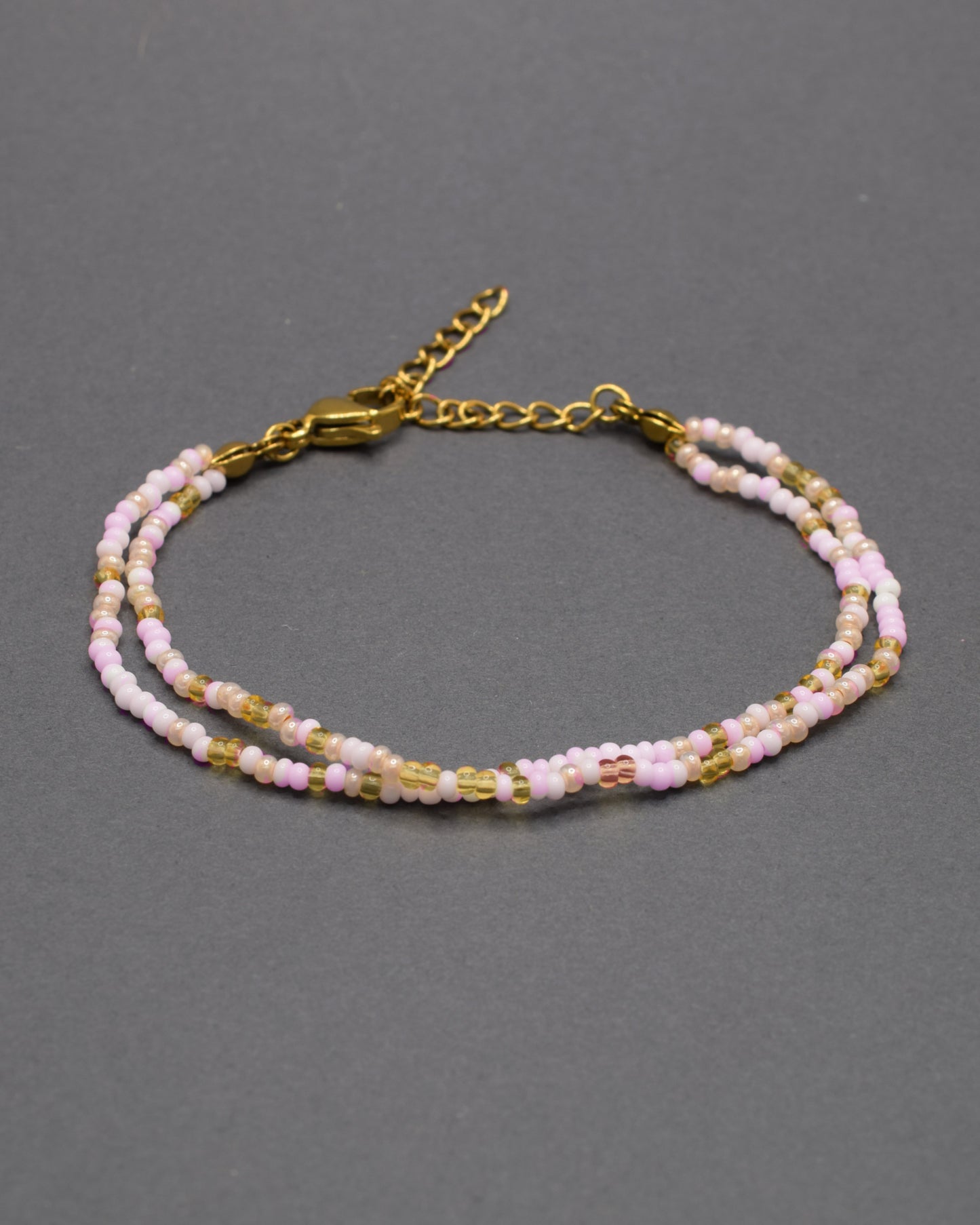 Pulseira dupla de missangas em tons de rosa e dourado, combinando delicadeza e estilo num design vibrante e elegante.