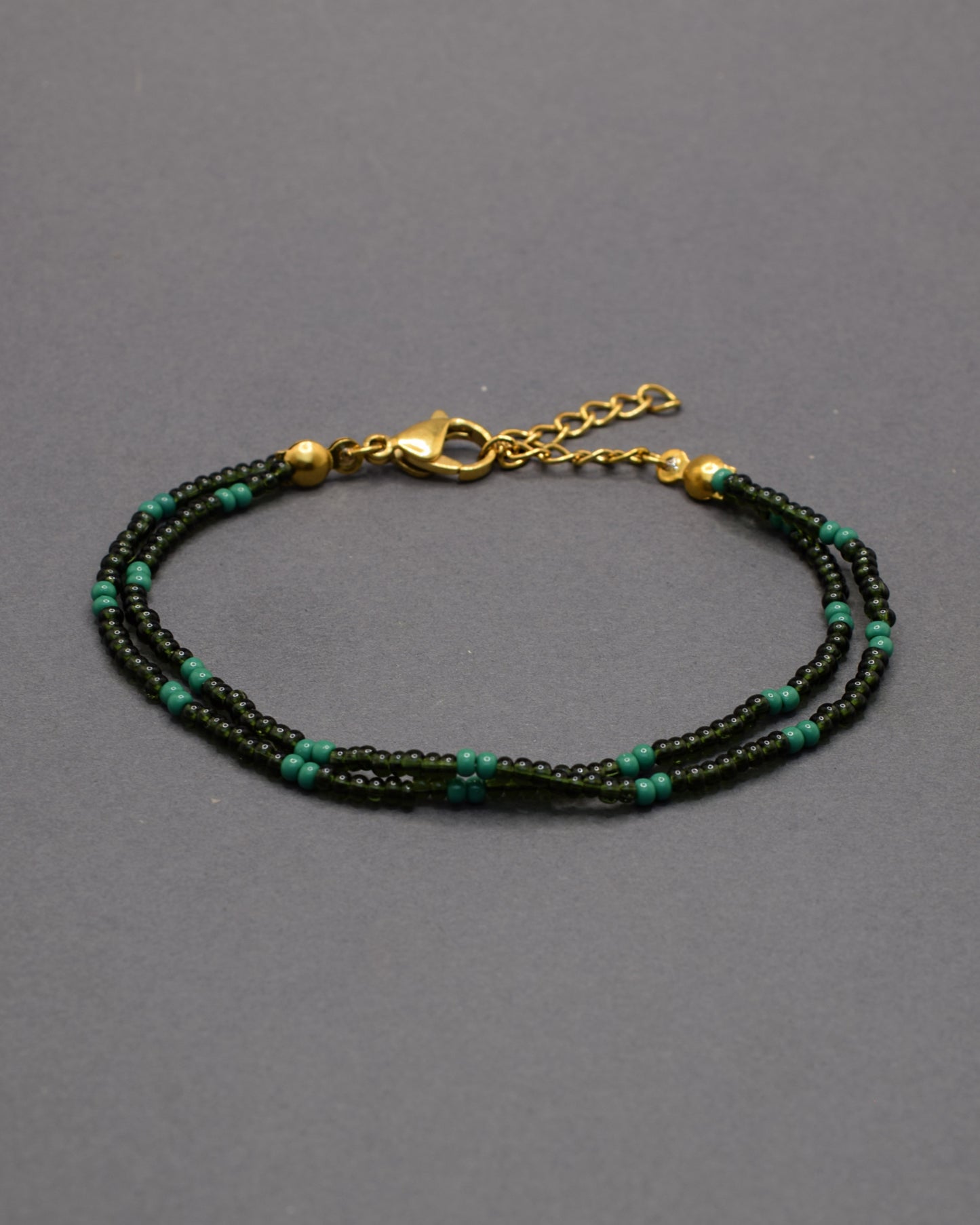 Pulseira dupla de missangas verde escuro semitransparentes em padrão elegante. Um acessório delicado e perfeito para complementar looks.