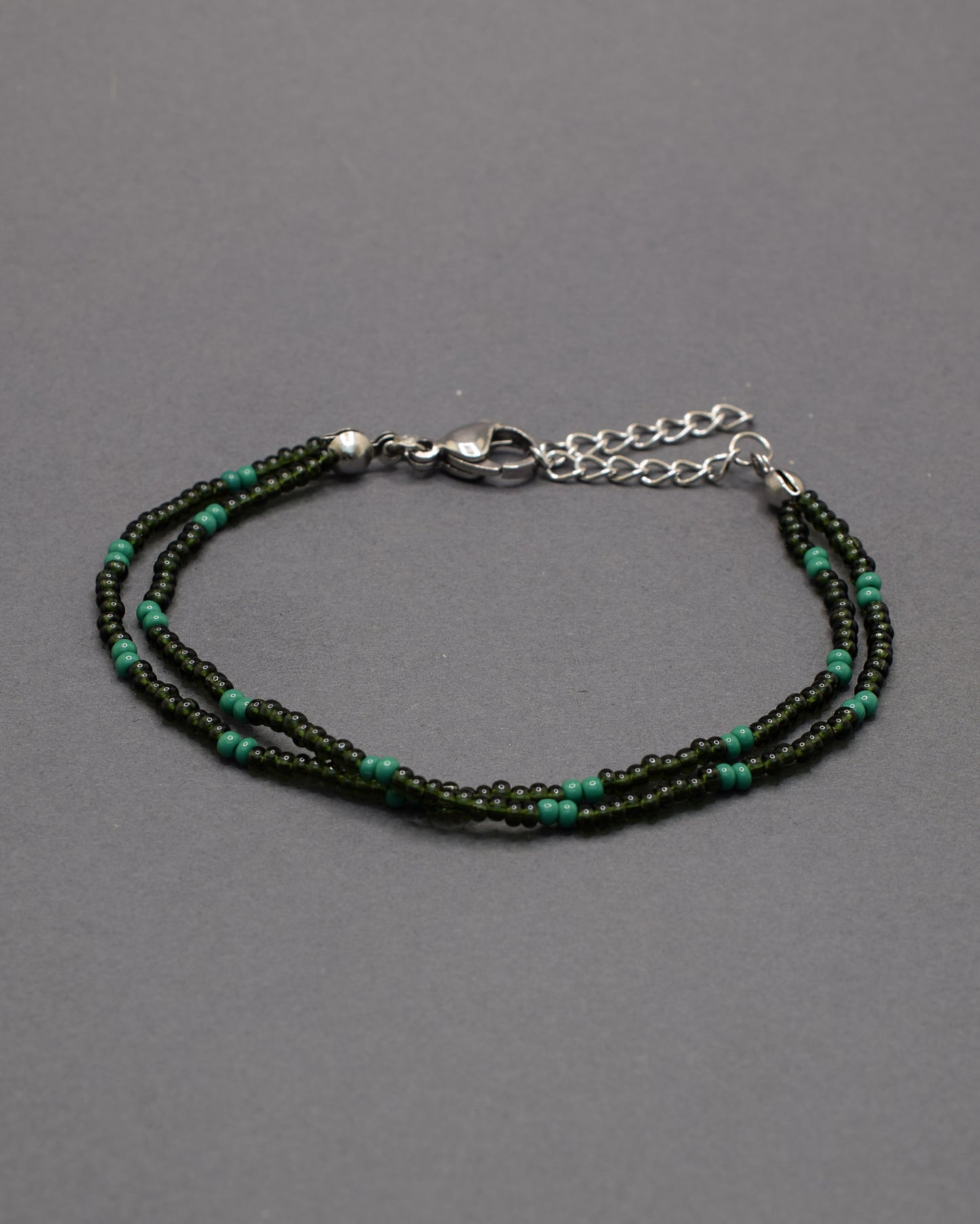 Pulseira dupla de missangas verde escuro semitransparentes em padrão elegante. Um acessório delicado e perfeito para complementar looks.
