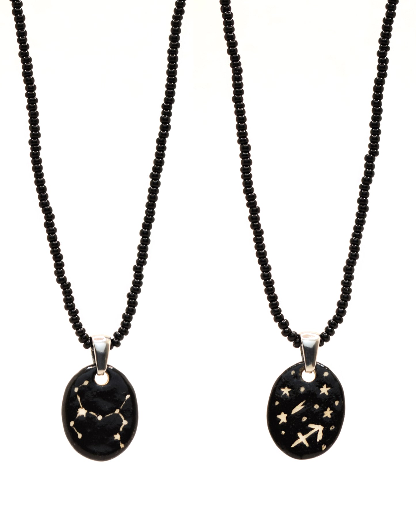 Colar elegante com pendente de cerâmica dupla-face representando a constelação Sagitário, adornado com missangas de vidro pretas para um toque sofisticado e misterioso.
