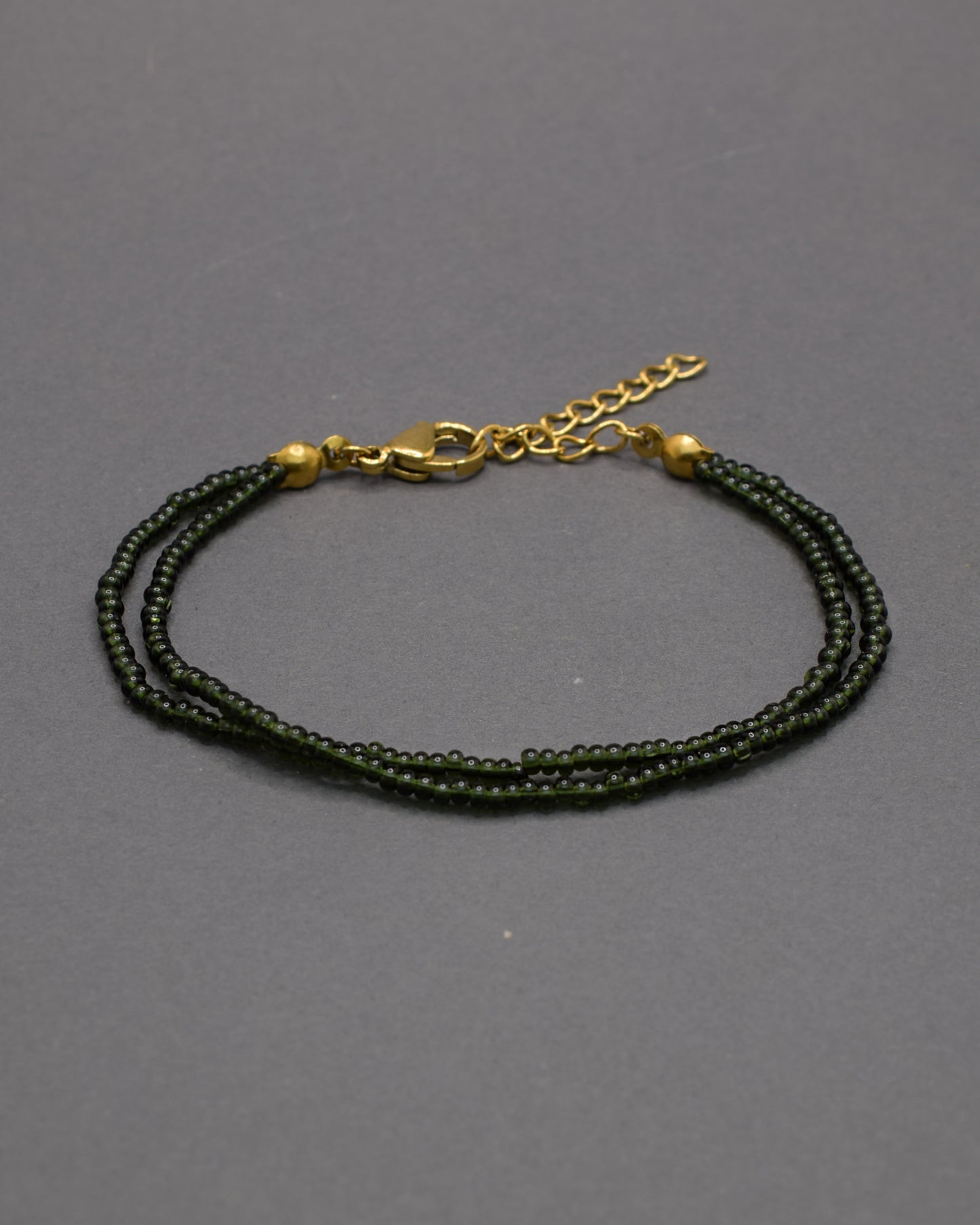 Pulseira dupla de missangas verde escuras semitransparentes. Design artesanal e elegante, ideal para um look sofisticado.