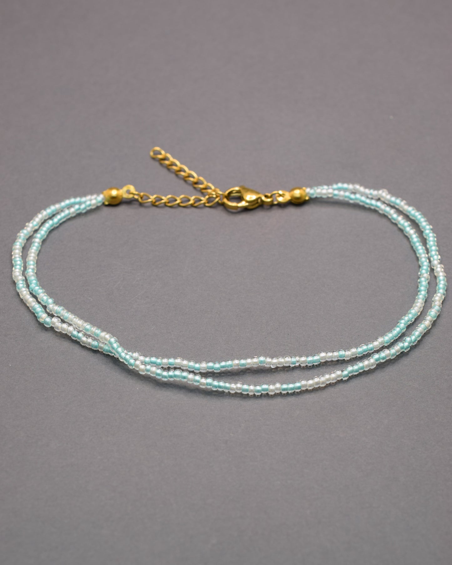 Pulseira dupla de tornozelo com missangas turquesa semitransparentes, leve e vibrante, ideal para um look fresco e cheio de estilo.