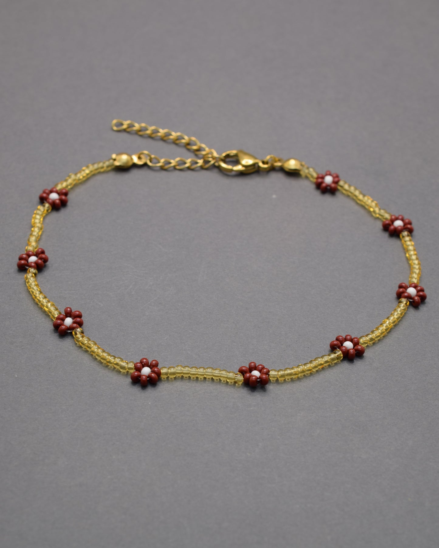 Pulseira de tornozelo em missangas verdes com flores brancas. Leve e fresca, ideal para um toque natural e delicado no teu estilo.