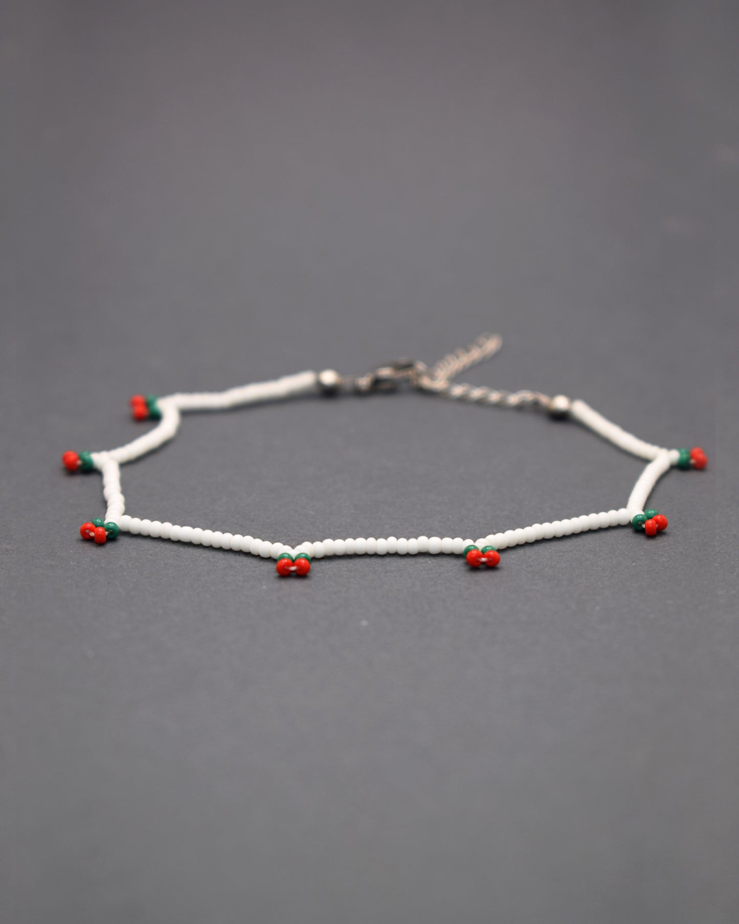 Delicie-se com a nossa Pulseira de Pé Cerejas de Missangas, uma joia artesanal feita em missangas de vidro que celebra a frescura do verão. Com um delicado bordado de cerejas vibrantes, esta pulseira é adornada com fecho em aço inoxidável hipoalergénico.