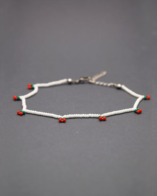 Delicie-se com a nossa Pulseira de Pé Cerejas de Missangas, uma joia artesanal feita em missangas de vidro que celebra a frescura do verão. Com um delicado bordado de cerejas vibrantes, esta pulseira é adornada com fecho em aço inoxidável hipoalergénico.