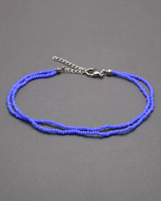Pulseira dupla de tornozelo em missangas de vidro azul neon, leve e vibrante, perfeita para destacar o teu estilo com um toque moderno e luminoso.
