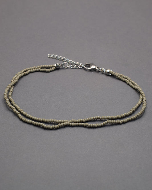 Pulseira dupla de tornozelo com missangas cinzentas. Elegante, discreta e perfeita para complementar qualquer look com estilo moderno.