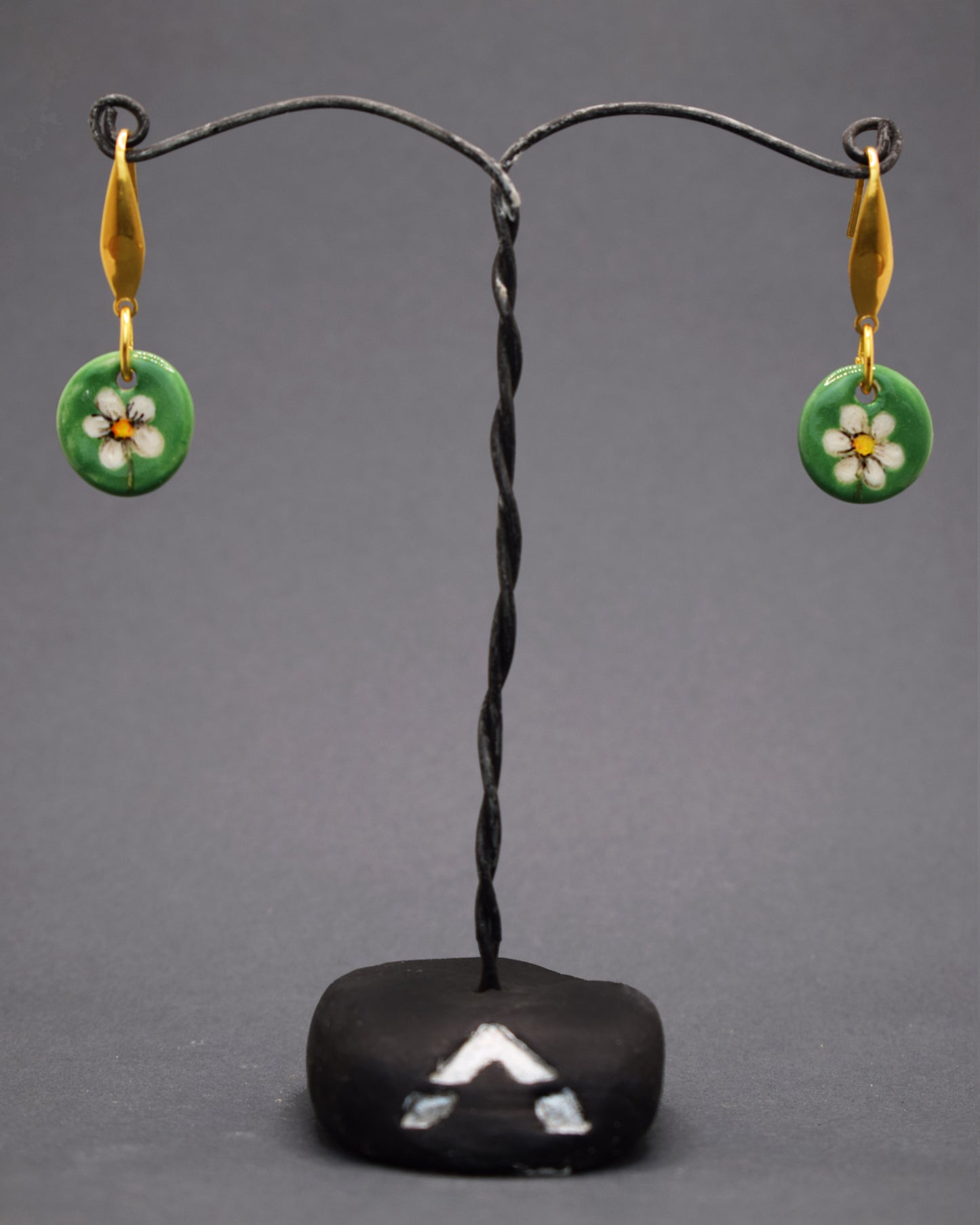 Adicione um toque natural ao seu estilo com brincos de aço inox dourado hipoalergénico. Com pendentes de cerâmica e margaridas pintadas à mão sobre fundo verde, eles combinam charme e frescor, destacando a arte e a delicadeza em cada detalhe. Perfeitos para qualquer ocasião.
