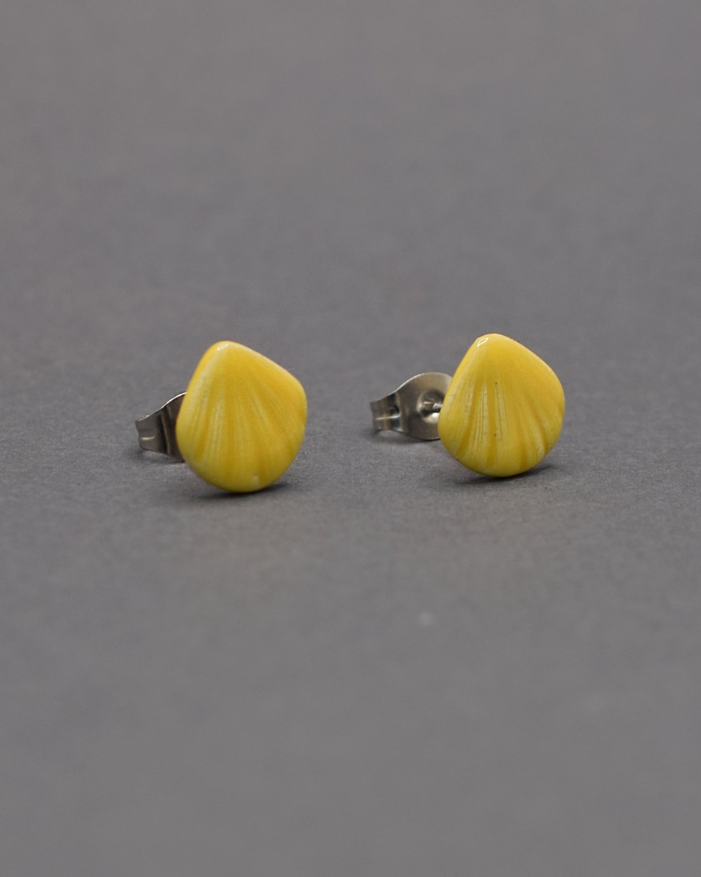 Brincos stud com conchas amarelas em cerâmica. Toque artesanal e vibrante para um look leve e cheio de cor.