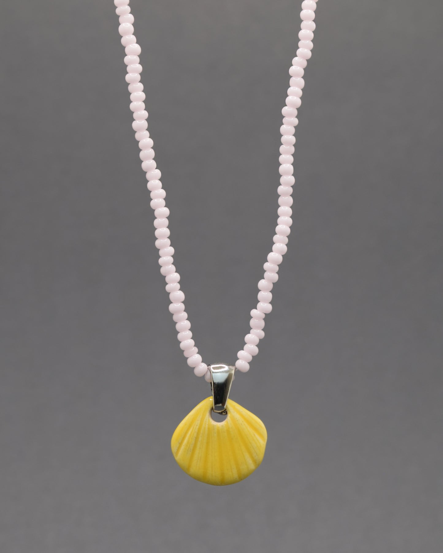 Colar com pendente de concha pintada em amarelo. Peça artesanal em cerâmica que celebra o verão com cor e elegância.