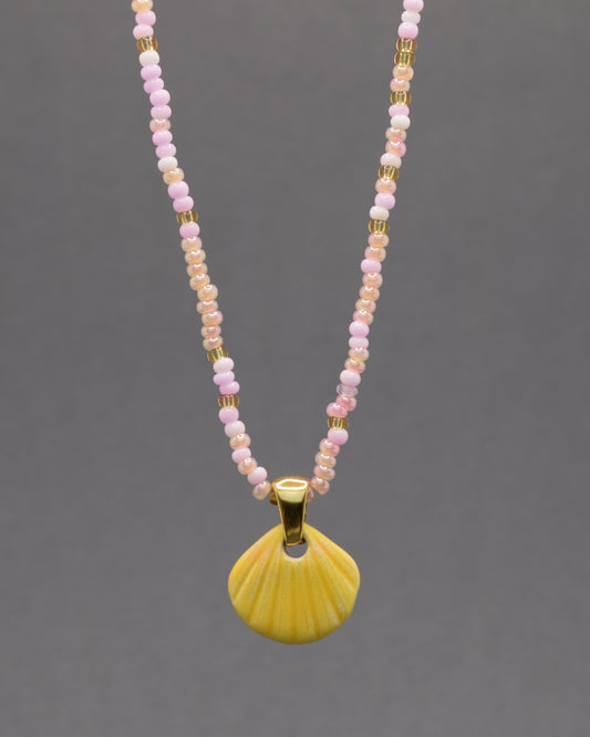 Colar com pendente de concha pintada em amarelo. Peça artesanal em cerâmica que celebra o verão com cor e elegância.