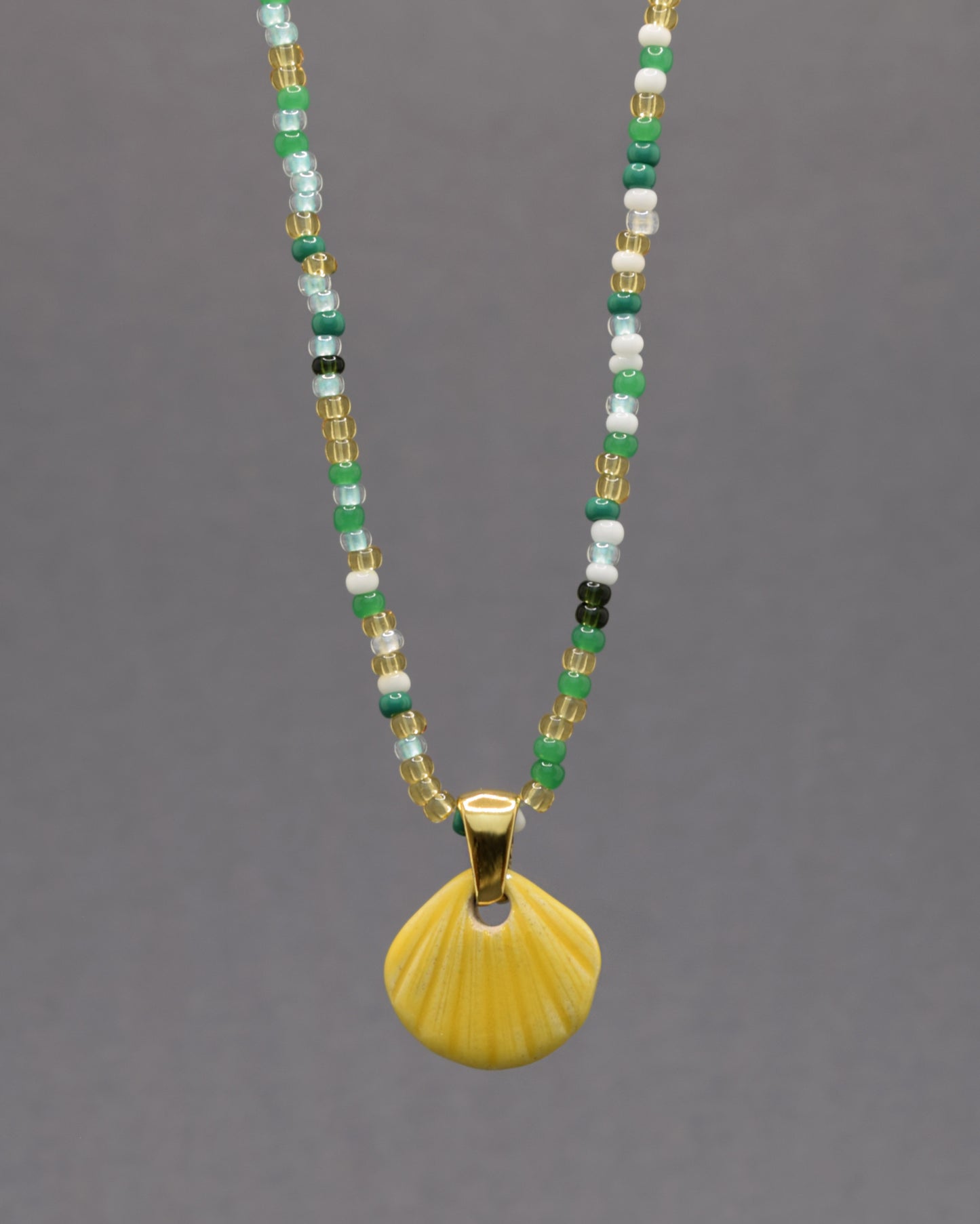 Colar com pendente de concha pintada em amarelo. Peça artesanal em cerâmica que celebra o verão com cor e elegância.