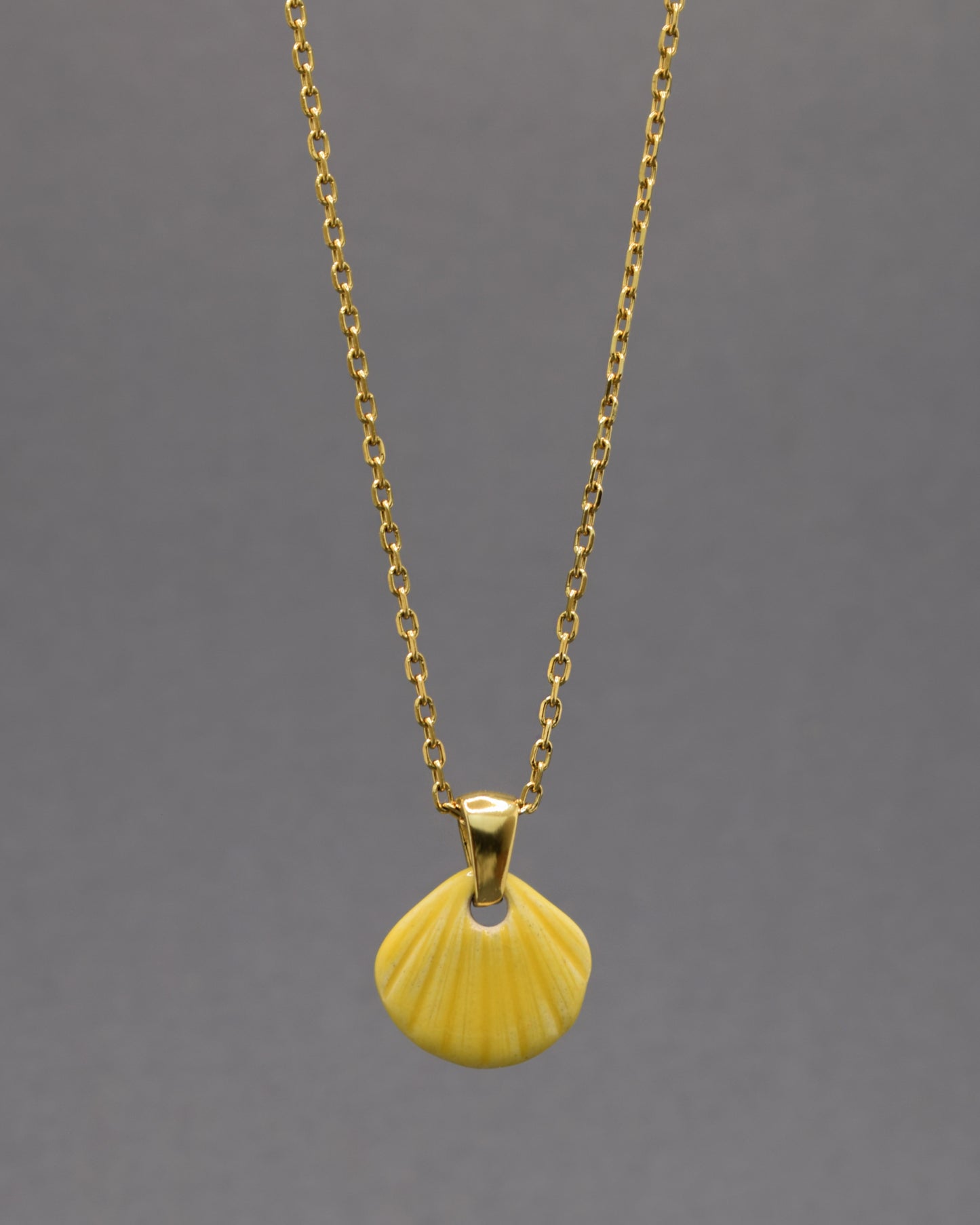 Colar com pendente de concha pintada em amarelo. Peça artesanal em cerâmica que celebra o verão com cor e elegância.