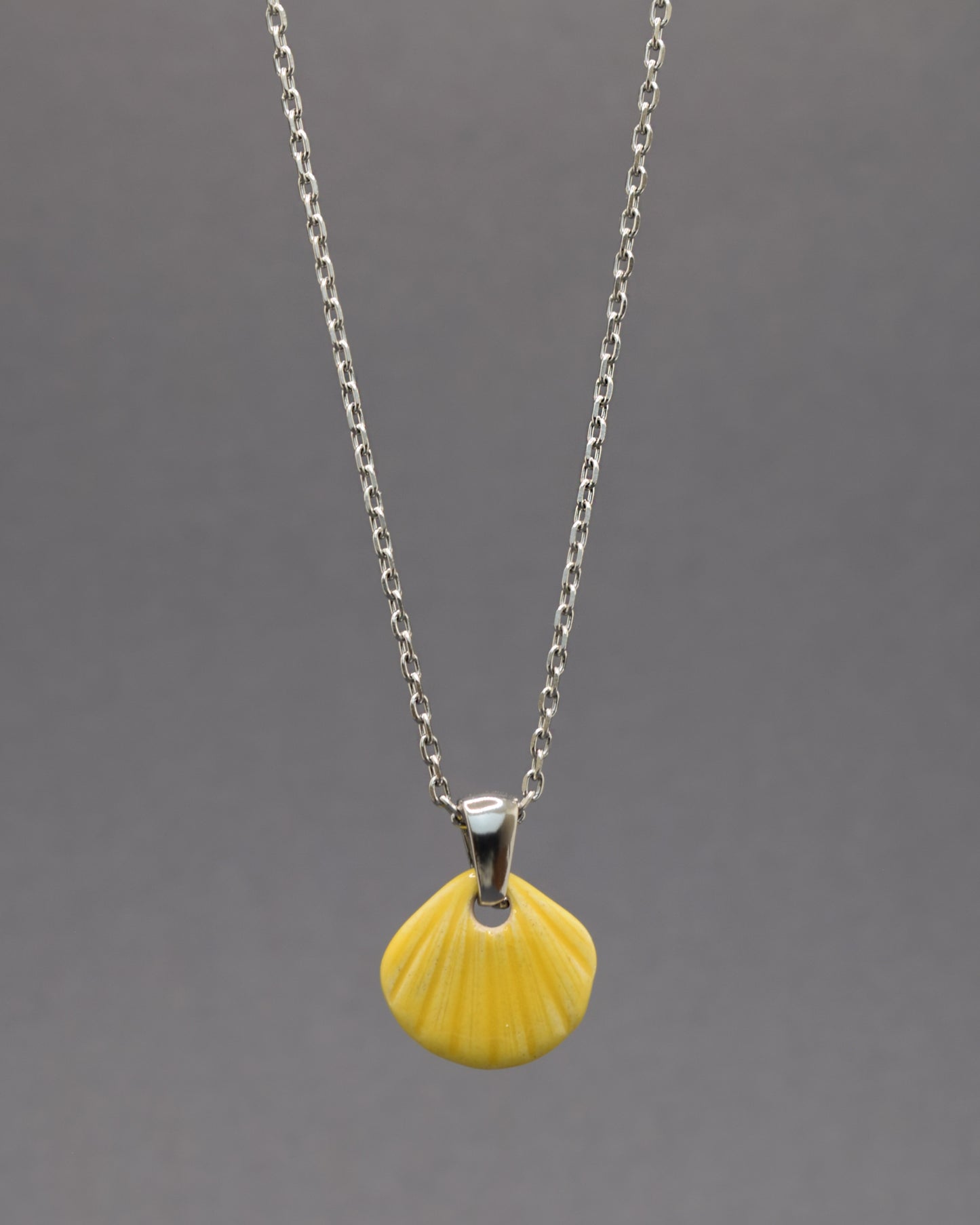 Colar com pendente de concha pintada em amarelo. Peça artesanal em cerâmica que celebra o verão com cor e elegância.