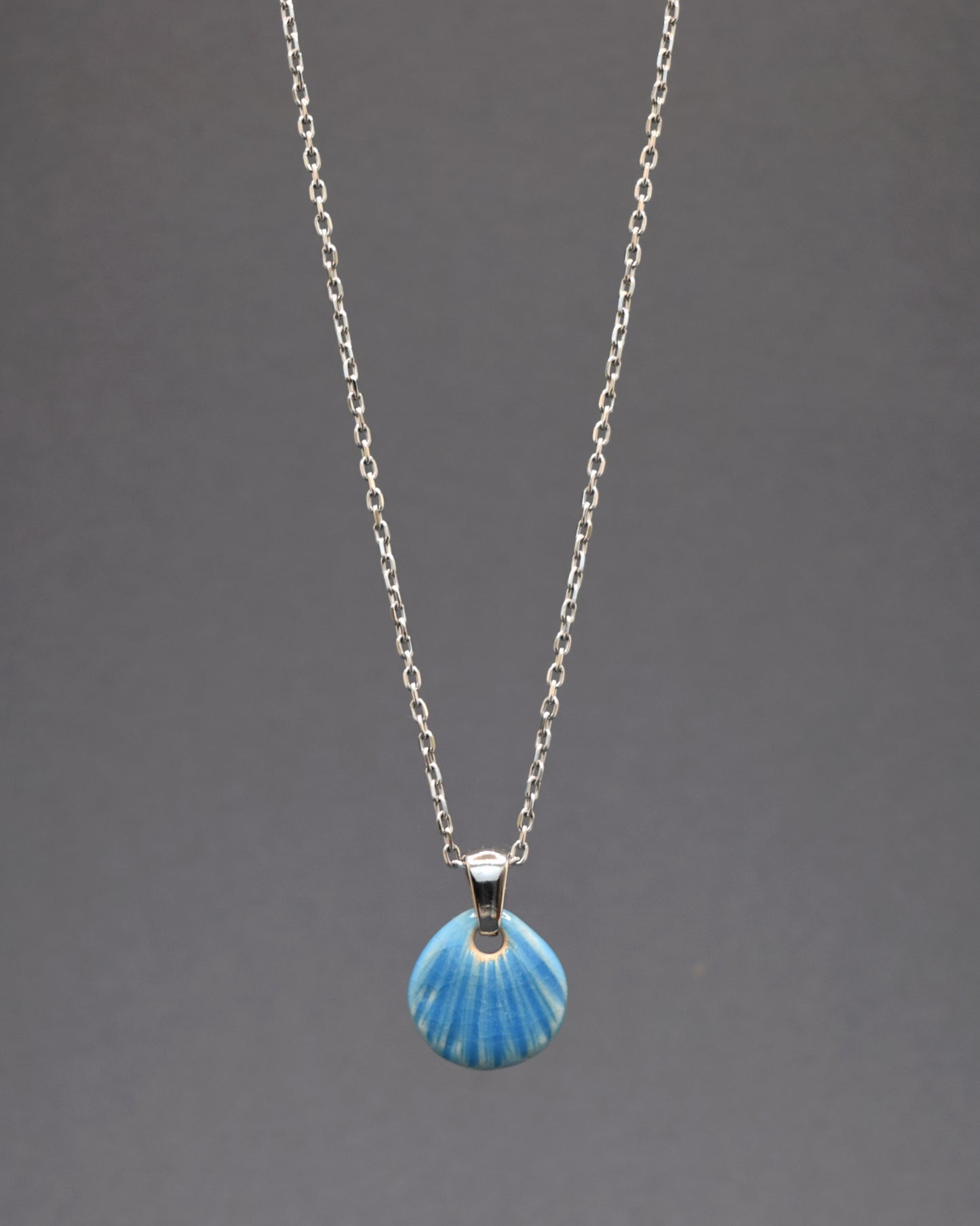 Colar em aço inoxidável com pendente de concha em cerâmica azul clara. Delicado e elegante, ideal para adicionar um toque único e sereno ao seu visual.