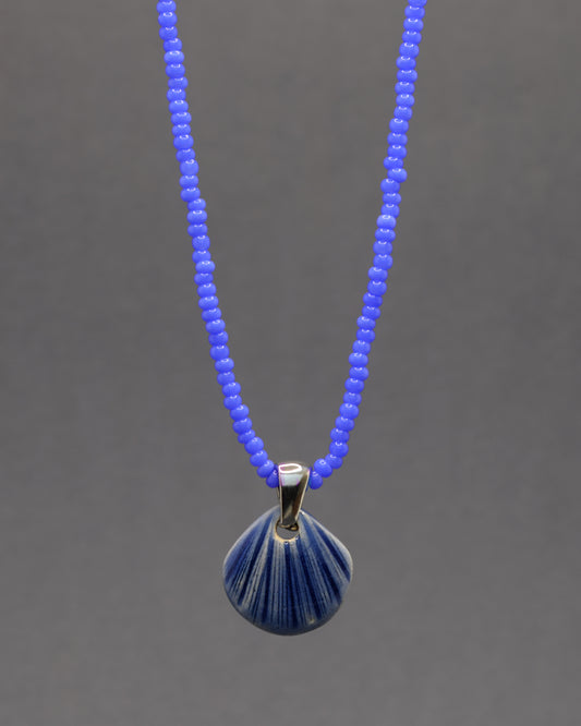Colar artesanal com pendente de concha em cerâmica azul escuro, inspirado no mar e na serenidade. Elegante e versátil para qualquer ocasião.