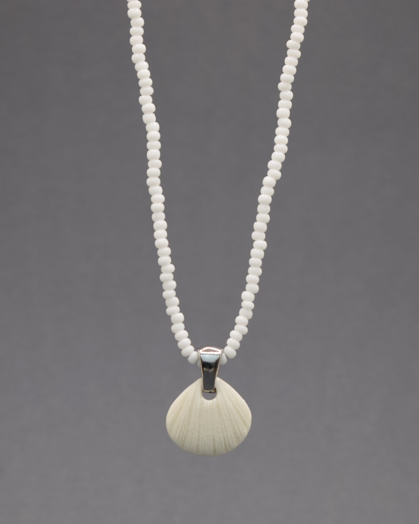 Colar com pendente de porcelana em forma de concha. Peça delicada, feita à mão, ideal para amantes do mar e do design artesanal.