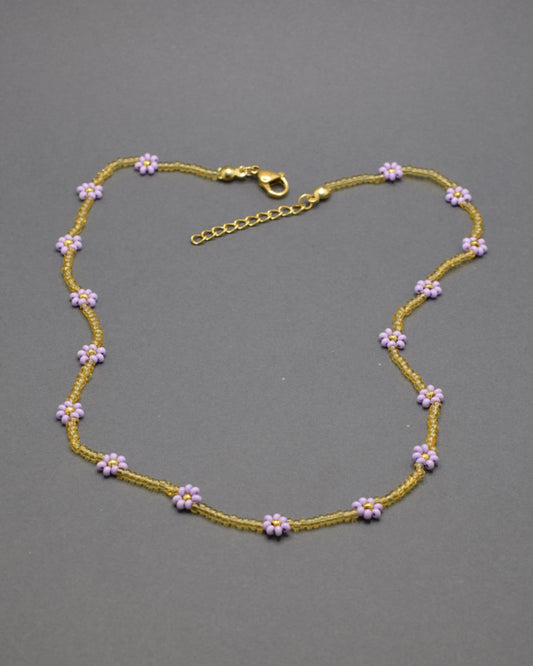 Adicione um toque de elegância e frescor ao seu visual com o nosso deslumbrante Colar de Missangas Douradas com Flores Roxas. Este colar exclusivo é artesanalmente confecionado com missangas de alta qualidade, formando um design harmonioso e delicado.