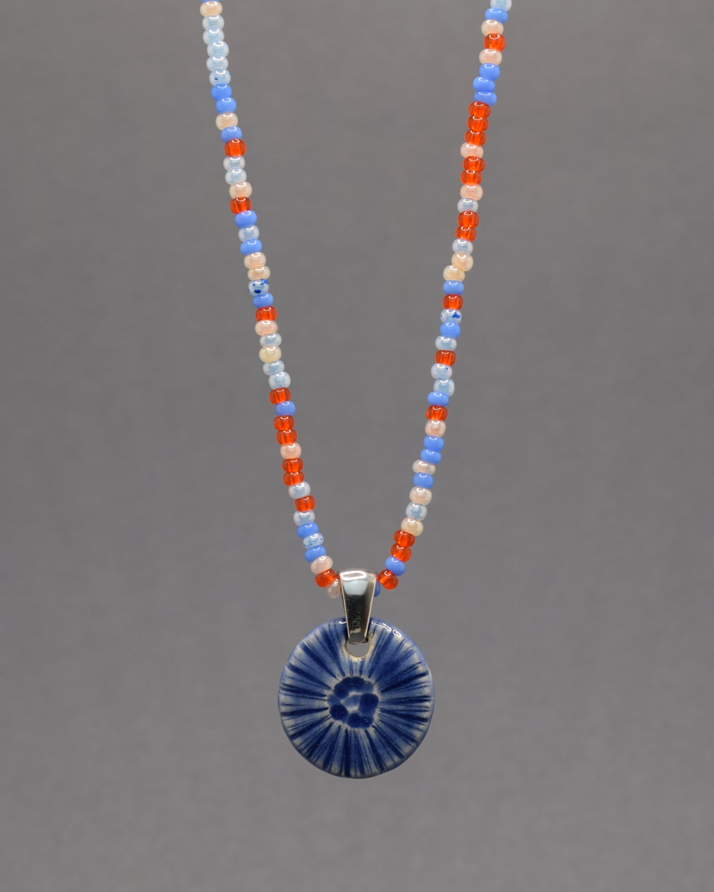 Colar artesanal em cerâmica azul escuro, inspirado na força do mar. Elegância contemporânea com acabamento único e orgânico.