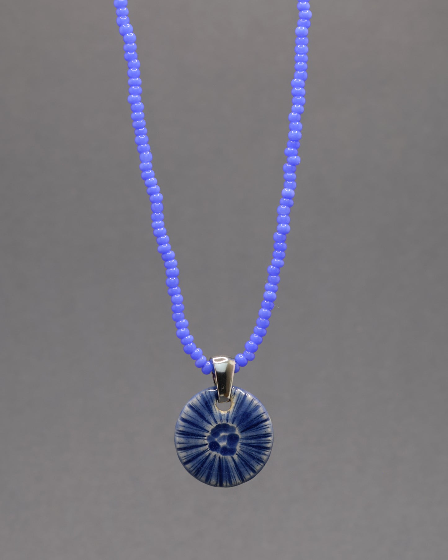 Colar artesanal em cerâmica azul escuro, inspirado na força do mar. Elegância contemporânea com acabamento único e orgânico.
