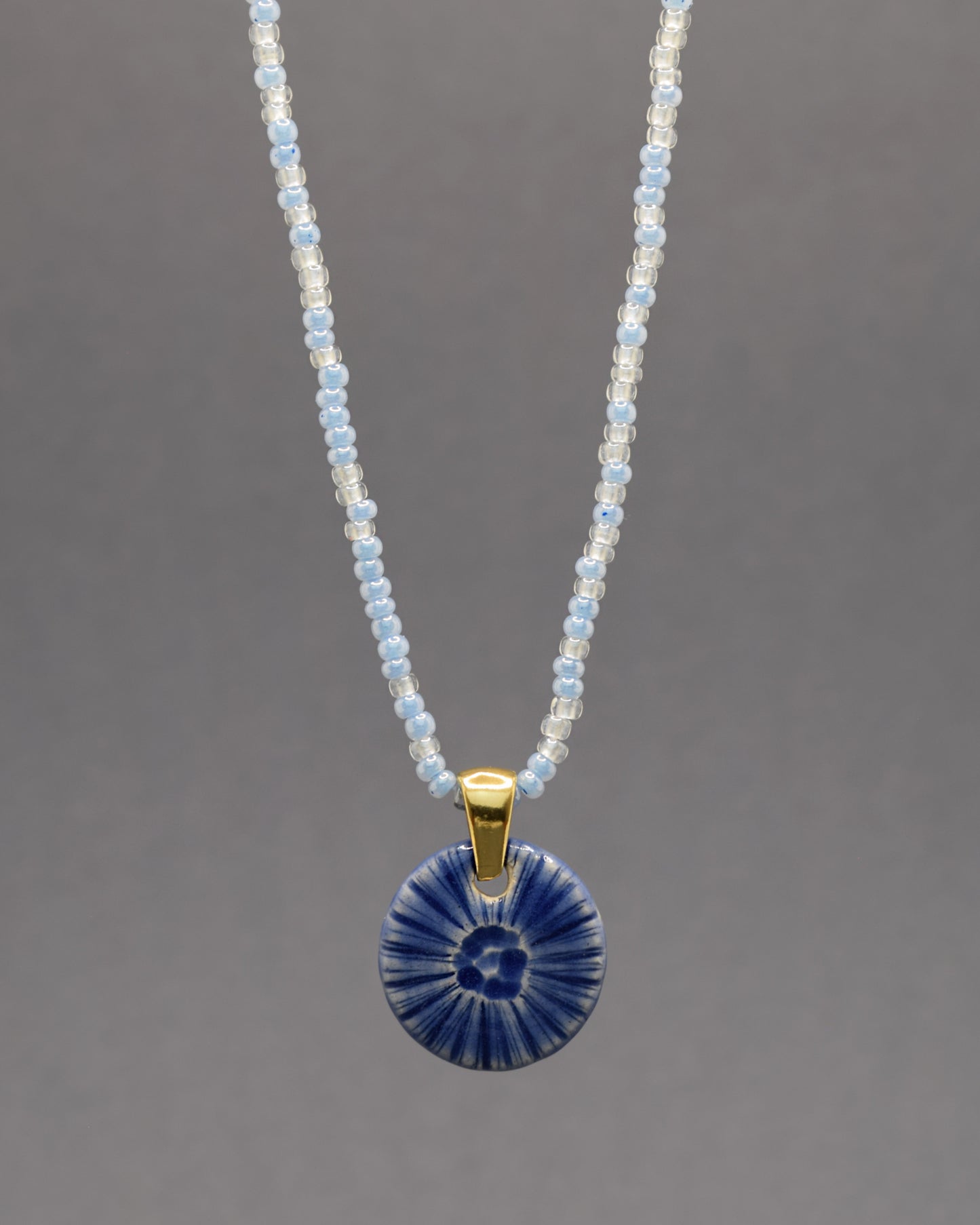 Colar artesanal em cerâmica azul escuro, inspirado na força do mar. Elegância contemporânea com acabamento único e orgânico.