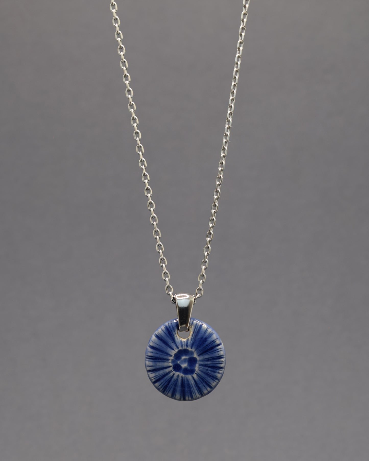 Colar artesanal em cerâmica azul escuro, inspirado na força do mar. Elegância contemporânea com acabamento único e orgânico.