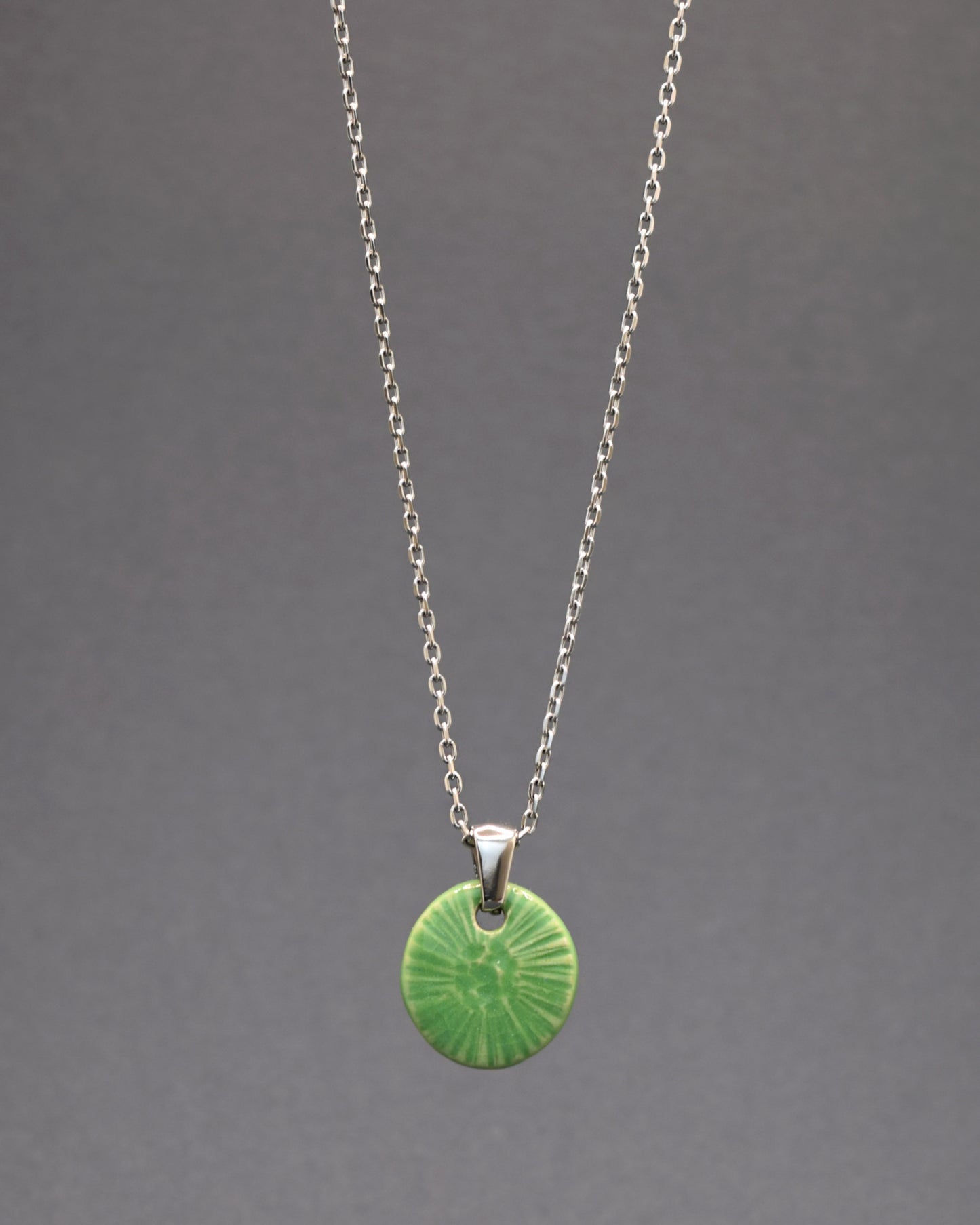 Este colar encantador destaca-se com um pendente em cerâmica feito à mão, inspirado na graciosa flor do mar em tonalidade verde alface. Montado em uma corrente de aço inoxidável, combina a elegância da cerâmica artesanal com a durabilidade do aço, criando uma peça única que harmoniza a natureza e o estilo contemporâneo.