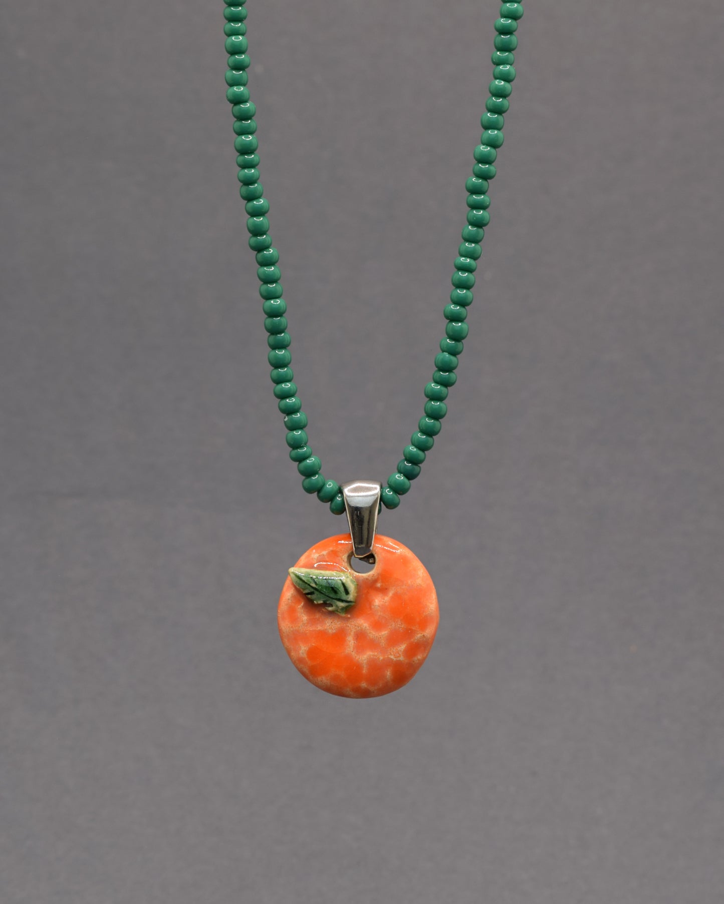 Colar com laranja e folha em cerâmica pintada à mão. Um apontamento de cor inspirado nos pomares portugueses, perfeito para dar vida a qualquer look.