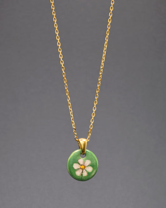 Explore a fusão de luxo e modernidade com este colar deslumbrante em aço inoxidável dourado. O pendente de cerâmica, adornado com uma graciosa margarida pintada à mão, destaca-se com elegância sobre o metal reluzente. Uma joia que transcende o comum, unindo o brilho sofisticado do aço inox dourado à delicadeza artesanal da cerâmica, proporcionando um toque refinado e contemporâneo ao seu estilo.