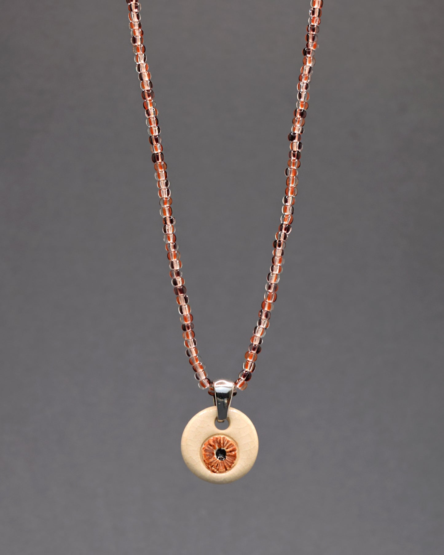 Envolva-se em charme e estilo com o nosso colar de missangas de vidro listradas castanhas, destacando um delicado pendente. Cada missanga é uma expressão única de elegância e as listras castanhas conferem uma vibração terrosa. Uma peça que combina a arte das missangas com a beleza discreta, perfeita para complementar seu visual com um toque de sofisticação casual.