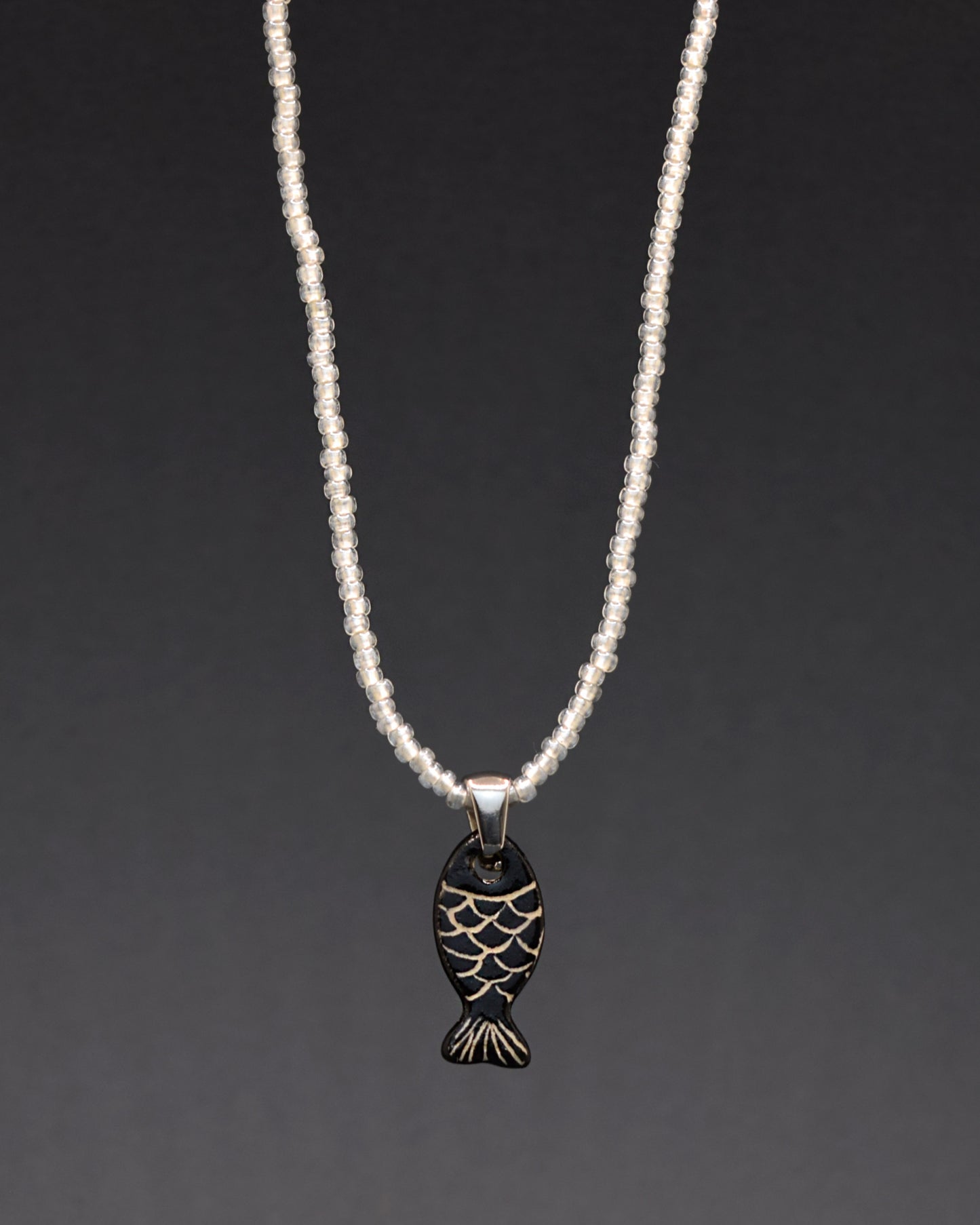 Pendente de cerâmica pintado à mão embeleza o nosso colar de missangas de vidro brancas semitransparentes. Uma fusão encantadora de artesanato delicado e elegância, este acessório único adiciona um toque de luz e sofisticação ao seu visual diário.