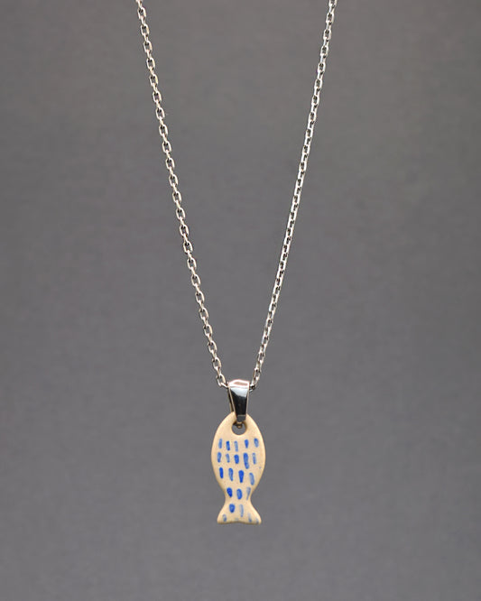  Colar em aço inoxidável com pendente de peixe em cerâmica, pintado à mão com delicadas pinceladas em azul, remetendo às escamas. Uma peça única que combina durabilidade com arte artesanal.