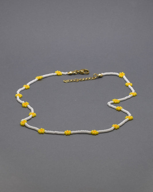 Adicione um toque de elegância e frescor ao seu visual com o nosso deslumbrante Colar de Missangas Brancas com Flores Amarelas. Este colar exclusivo é artesanalmente confecionado com missangas de alta qualidade, formando um design harmonioso e delicado.