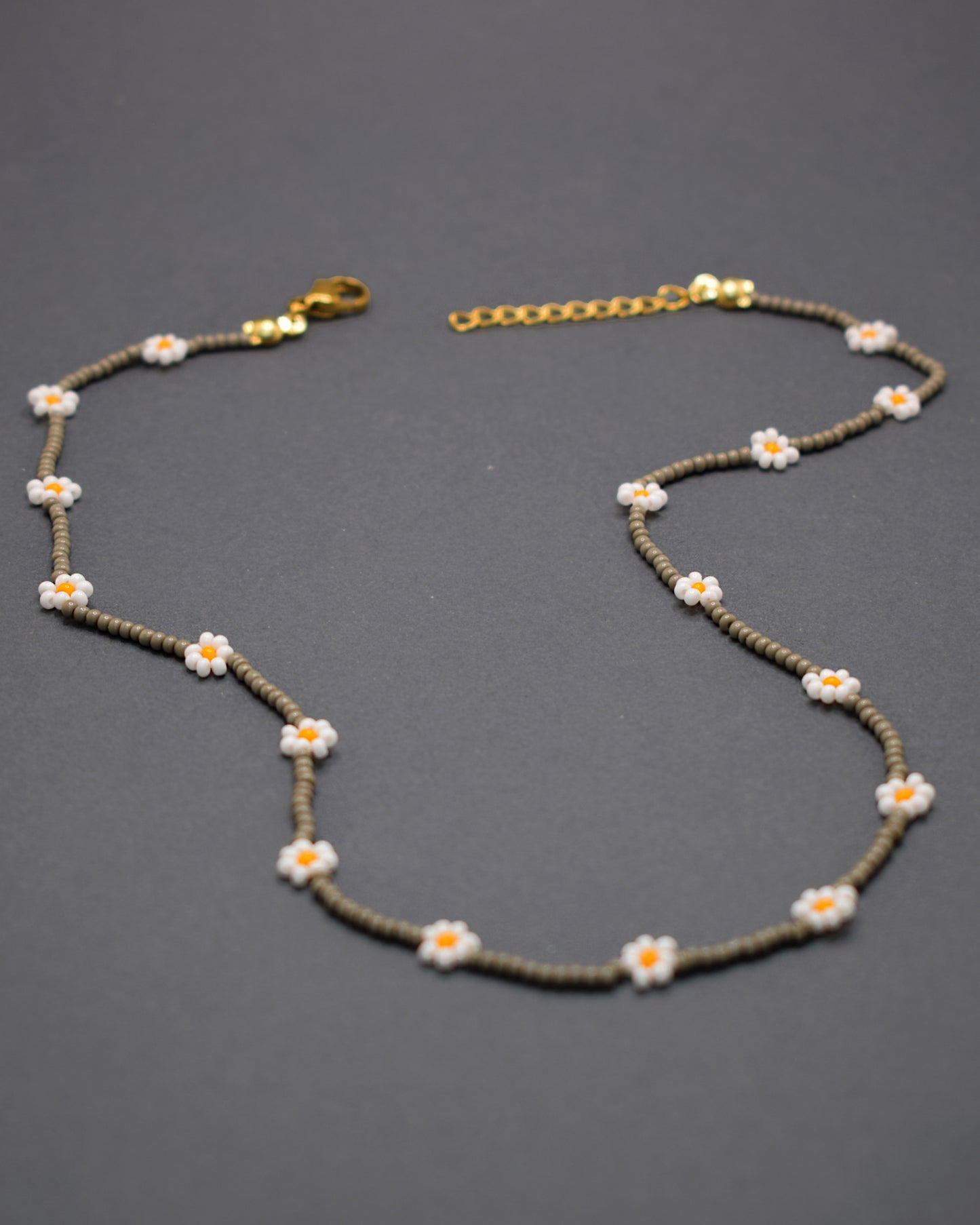 Adicione um toque de elegância e frescor ao seu visual com o nosso deslumbrante Colar de Missangas Cinzentas com Flores Brancas. Este colar exclusivo é artesanalmente confecionado com missangas de alta qualidade, formando um design harmonioso e delicado.