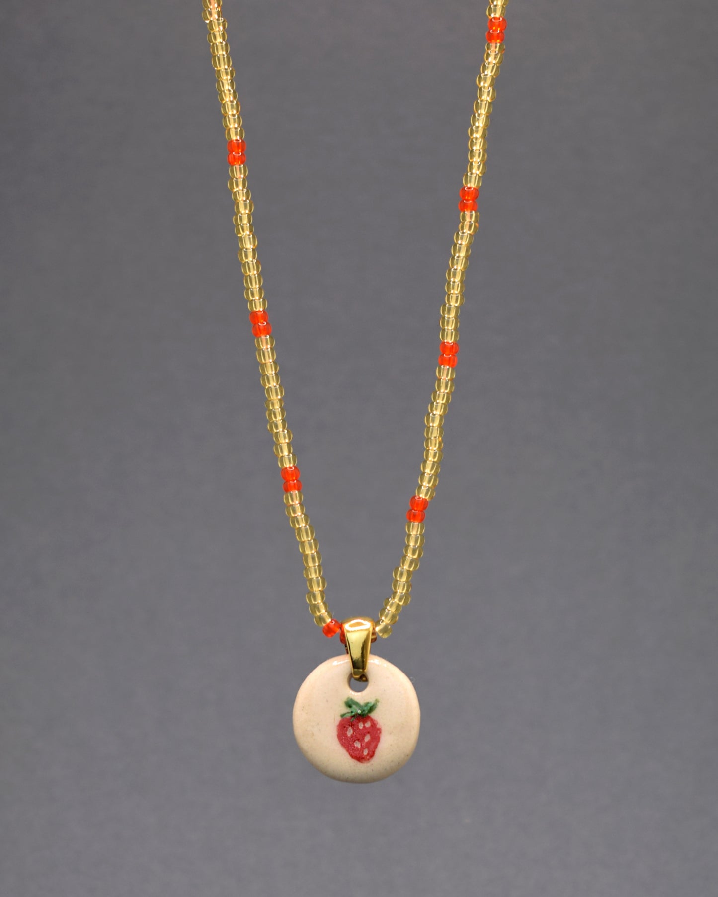 Deslumbre-se com a exclusividade do nosso colar, apresentando um pendente de cerâmica pintado à mão, suspenso por missangas de vidro douradas semitransparentes com um padrão bordô. Esta fusão de luxo e artesanato cria uma peça elegante e única, adicionando um toque de brilho e refinamento ao seu estilo pessoal.