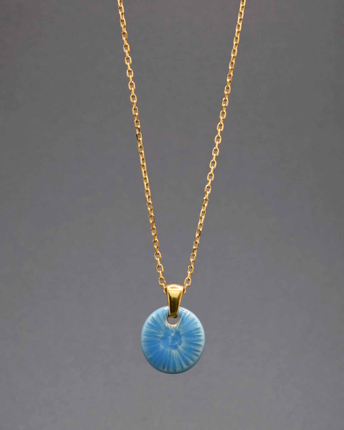 Colar cativante em aço inoxidável dourado, destacando um gracioso pendente azul celeste inspirado na beleza de uma flor do mar. Uma peça singular que adiciona um toque distintivo e encantador ao seu estilo.