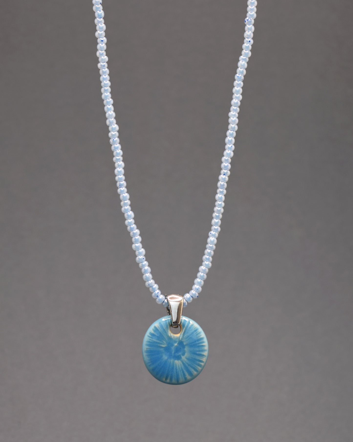 Colar cativante com missangas de vidro azul claro, complementado por um delicado pendente azul celeste inspirado na beleza de uma flor do mar. Uma peça singular que adiciona um toque distintivo e encantador ao seu estilo.