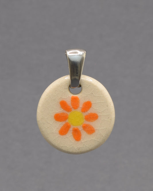 Pendente de cerâmica pintado à mão com uma delicada margarida laranja. As cores vibrantes e o acabamento artesanal tornam cada peça única e cheia de encanto.