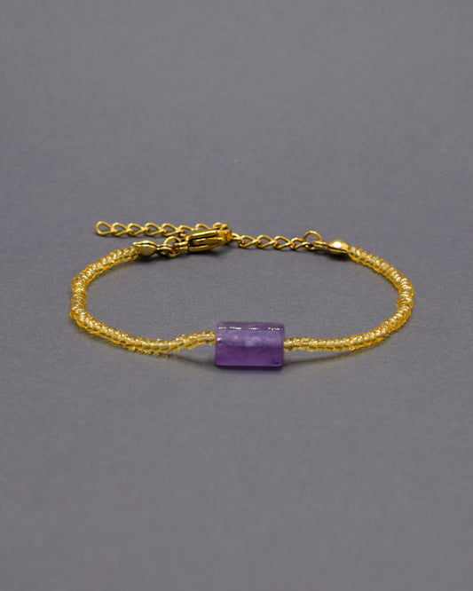 Pulseira de ametista natural, símbolo de equilíbrio e proteção, com missangas douradas semitransparentes.