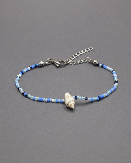 Pulseira com búzio natural e missangas de vidro em azul profundo, moderna e marcante, perfeita para um estilo autêntico com destaque subtil.