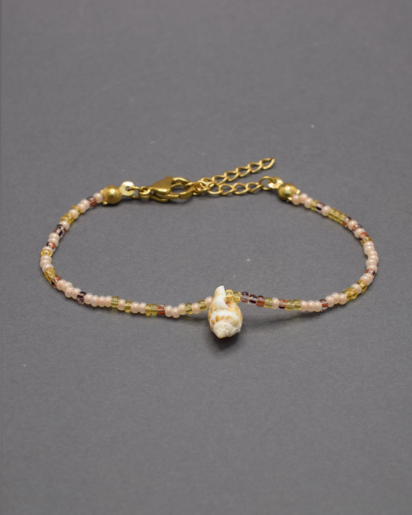 Pulseira Búzio de missangas em mix dourado, combinando brilho suave e detalhes naturais para um look elegante e leve, perfeito para o verão.