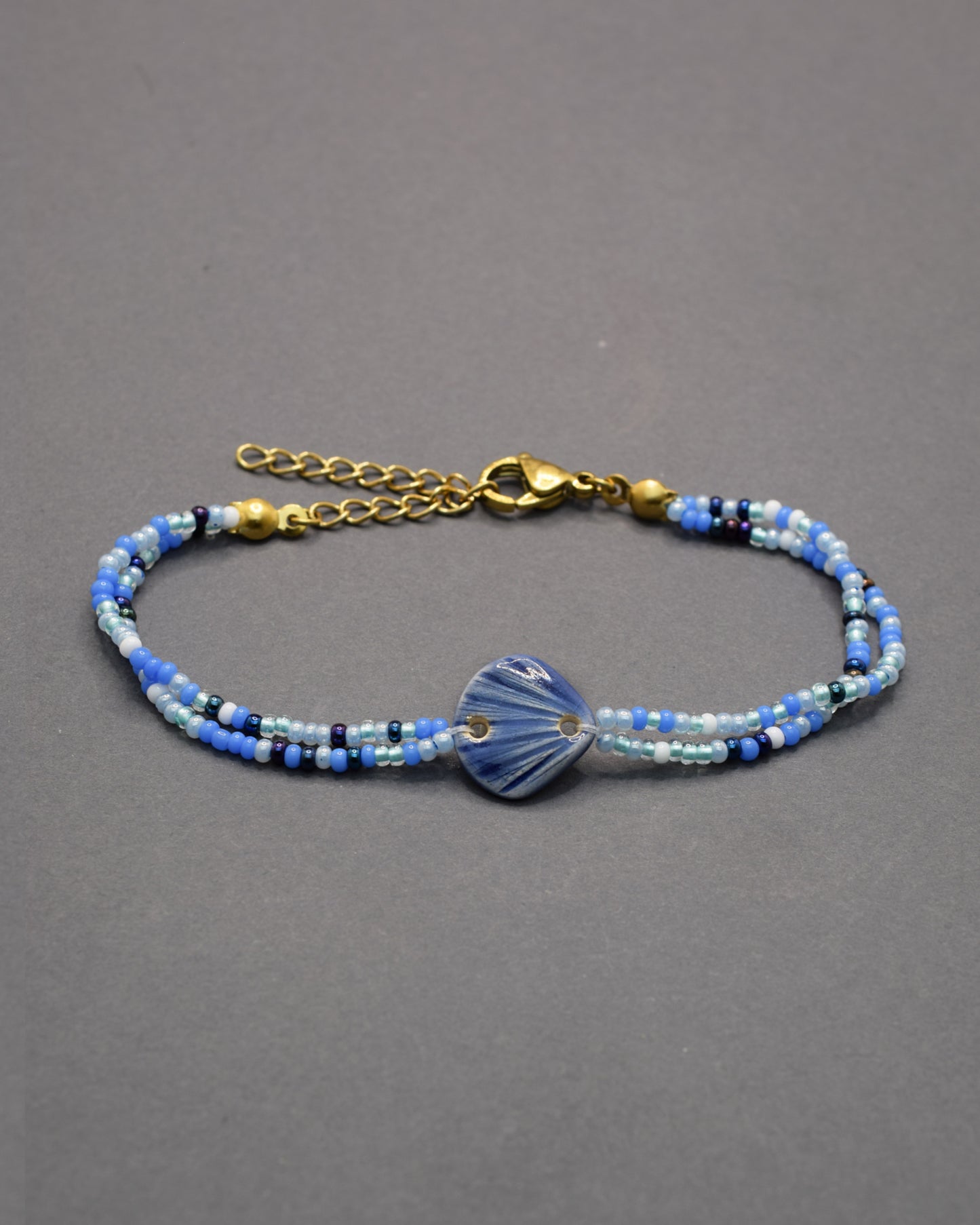 Pulseira com pendente de cerâmica em forma de concha azul escuro, elegante e sofisticada, ideal para um toque marítimo e refinado no seu look.